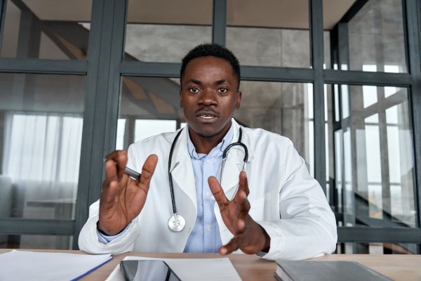 A black male doctor facing a camera discussing a topic.