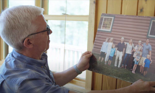A picture of a man looking at a picture of family members.