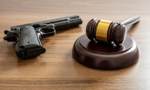 Judge gavel and handgun on lawyer's office desk.