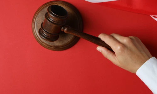 Female judge holds gavel on red background.